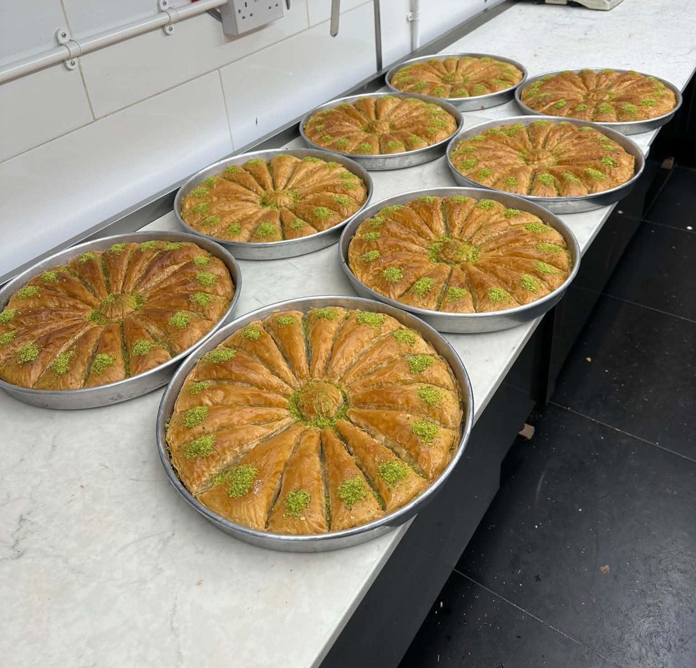 Round trays of pistachio baklava on the kitchen counter
